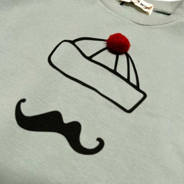 Light green sweatshirt with a black beanie and mustache design on a light green background