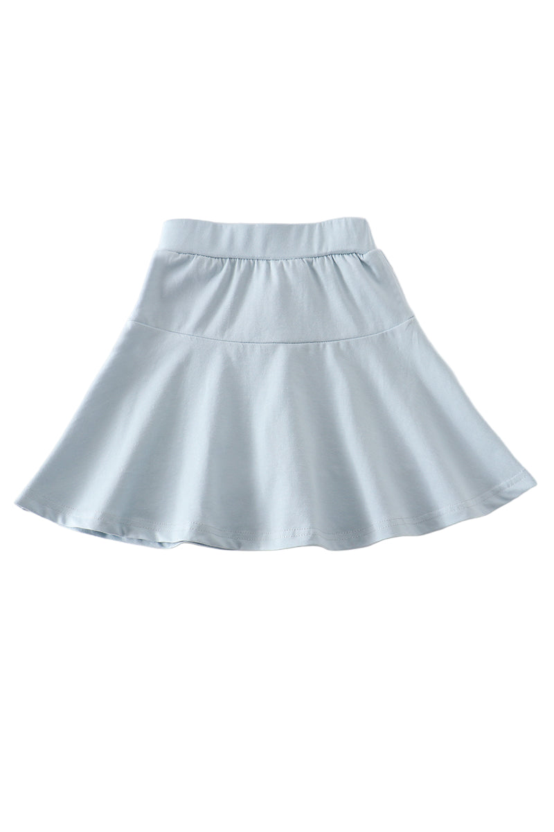 A blue skort with a flare skirt design and a solid color appearance, displayed against a light pink background.