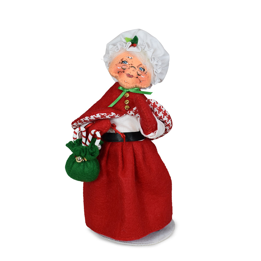 Annalee 9 inch Jubilee Mrs. Santa doll in a red felt skirt and coat lined with houndstooth, holding a green bag of candy canes