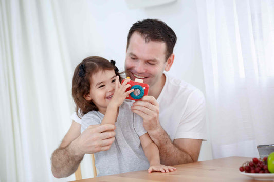 Man and young girl holding a toy together in a bright room