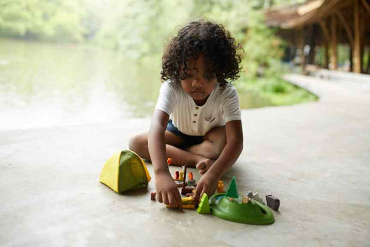Child playing with toy camping set on a path outdoors