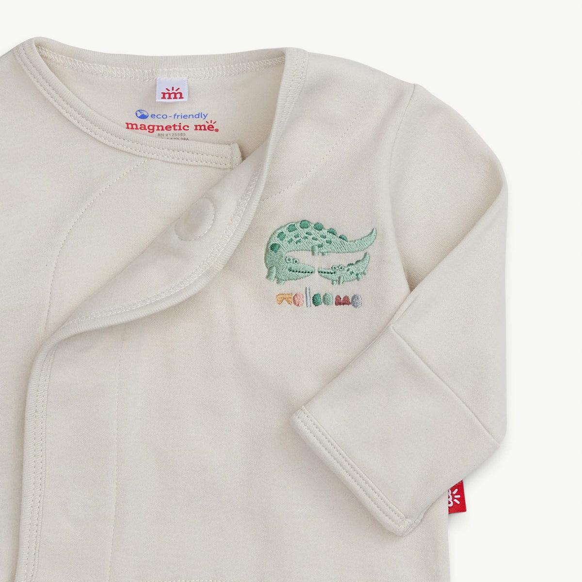 Baby onesie with alligator design and 'magnetic me' label on a white background