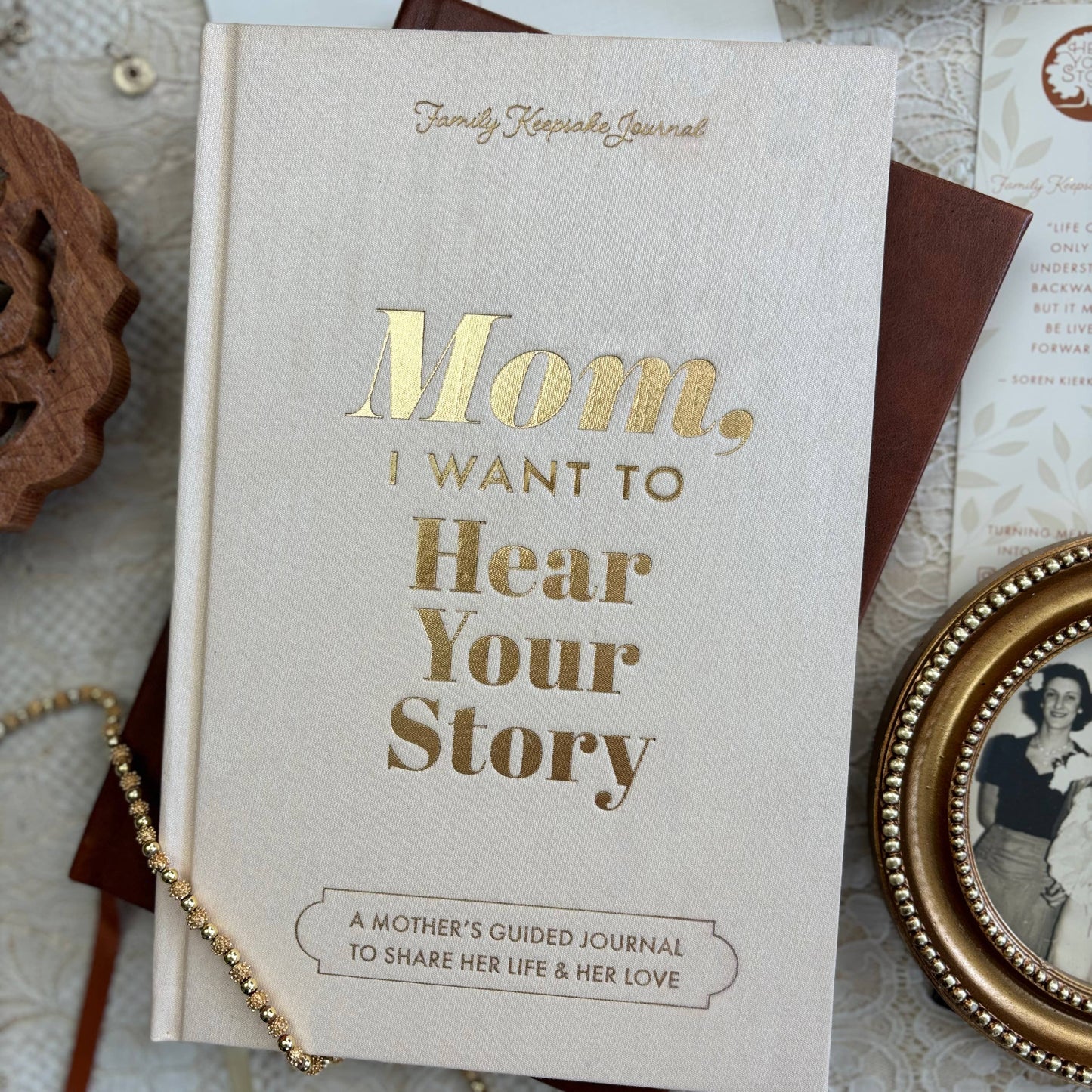 Book titled 'Mom, I Want to Hear Your Story' on a textured surface with decorative items.