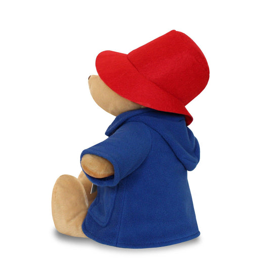 Stuffed bear toy wearing a blue coat and red hat on a white background