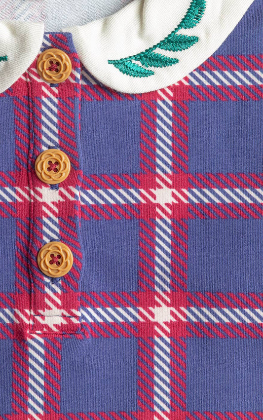 Close-up of a plaid dress with buttons and embroidery on a white background