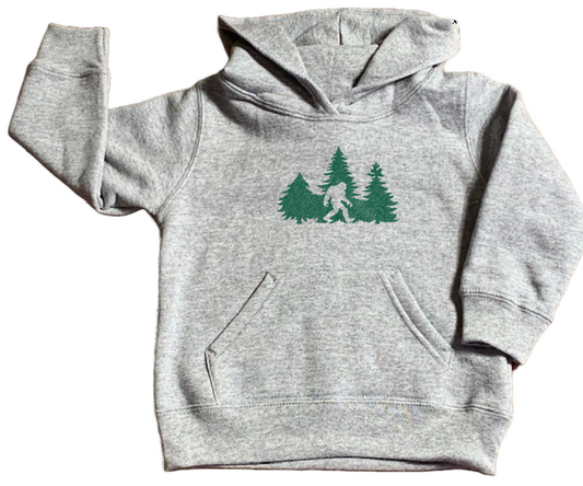 Gray hoodie with green graphic of a forest and bigfoot on a white background