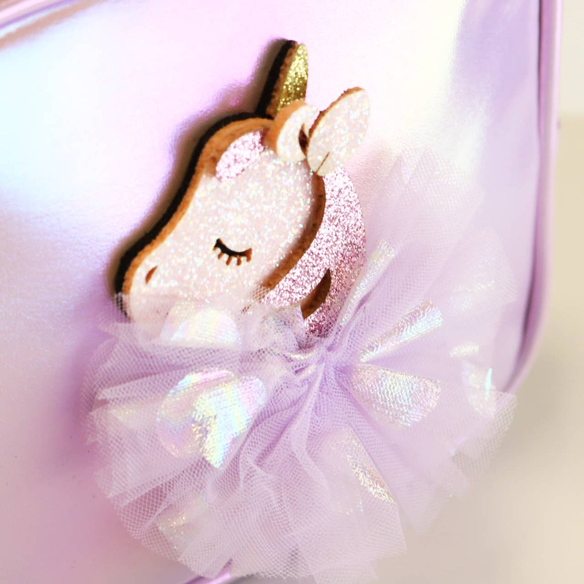 Unicorn-shaped with a gold horn on a pink purse with a purple bow