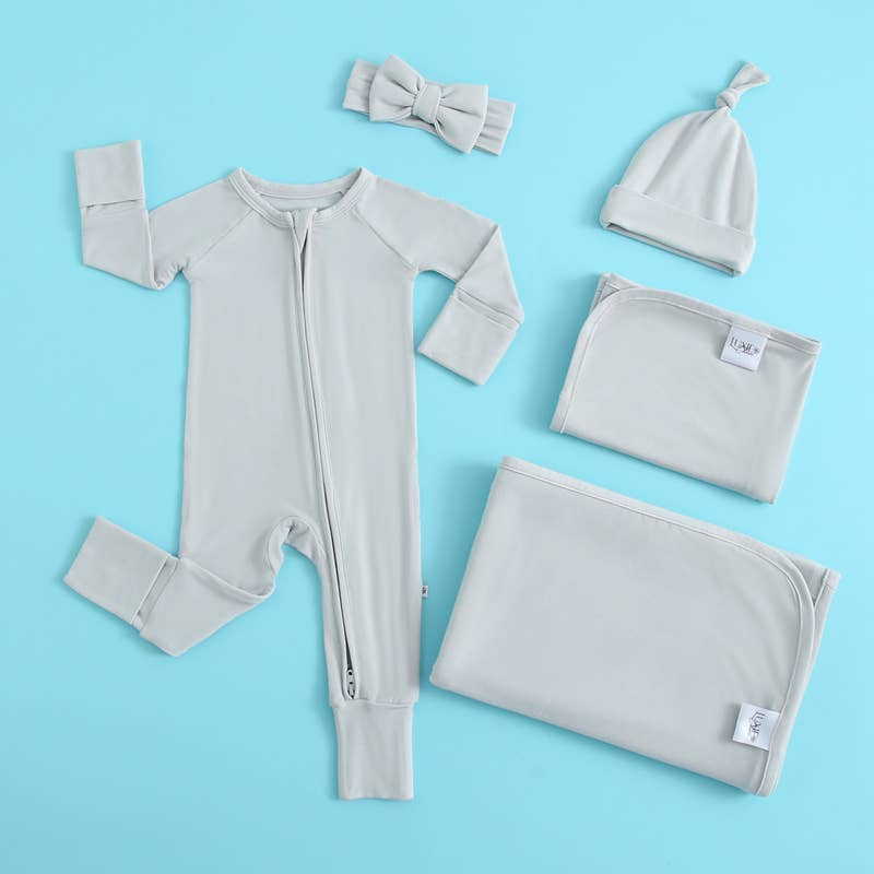 Baby clothing set with onesie, hat, blanket, and headband on a blue background