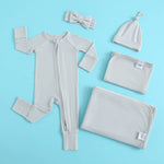 Baby clothing set with onesie, hat, blanket, and headband on a blue background