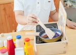 Child playing with a toy kitchen set on a wooden table