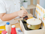 Child playing with toy kitchen set on a wooden table