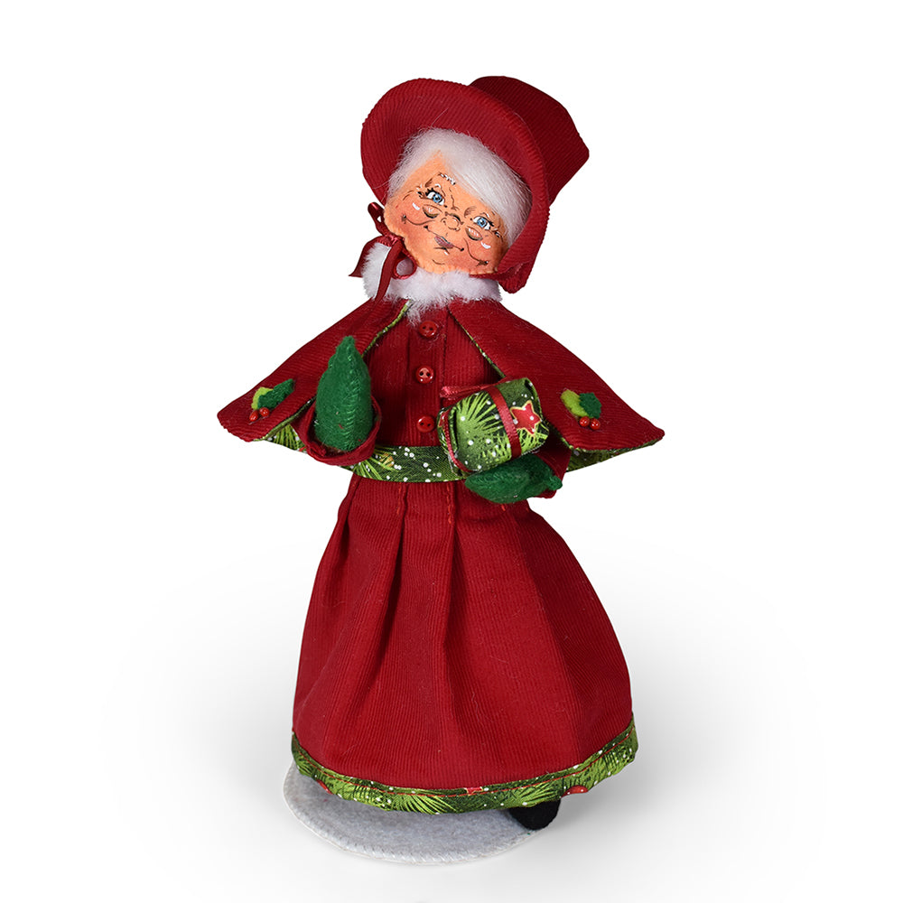 Annalee 9in Yuletide Mrs. Santa in red corduroy dress and shawl cloak holding a gift wrapped in evergreen paper