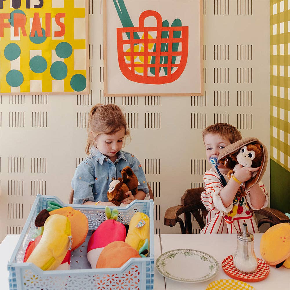 Two children playing with toys in a colorful room with wall art and furniture.