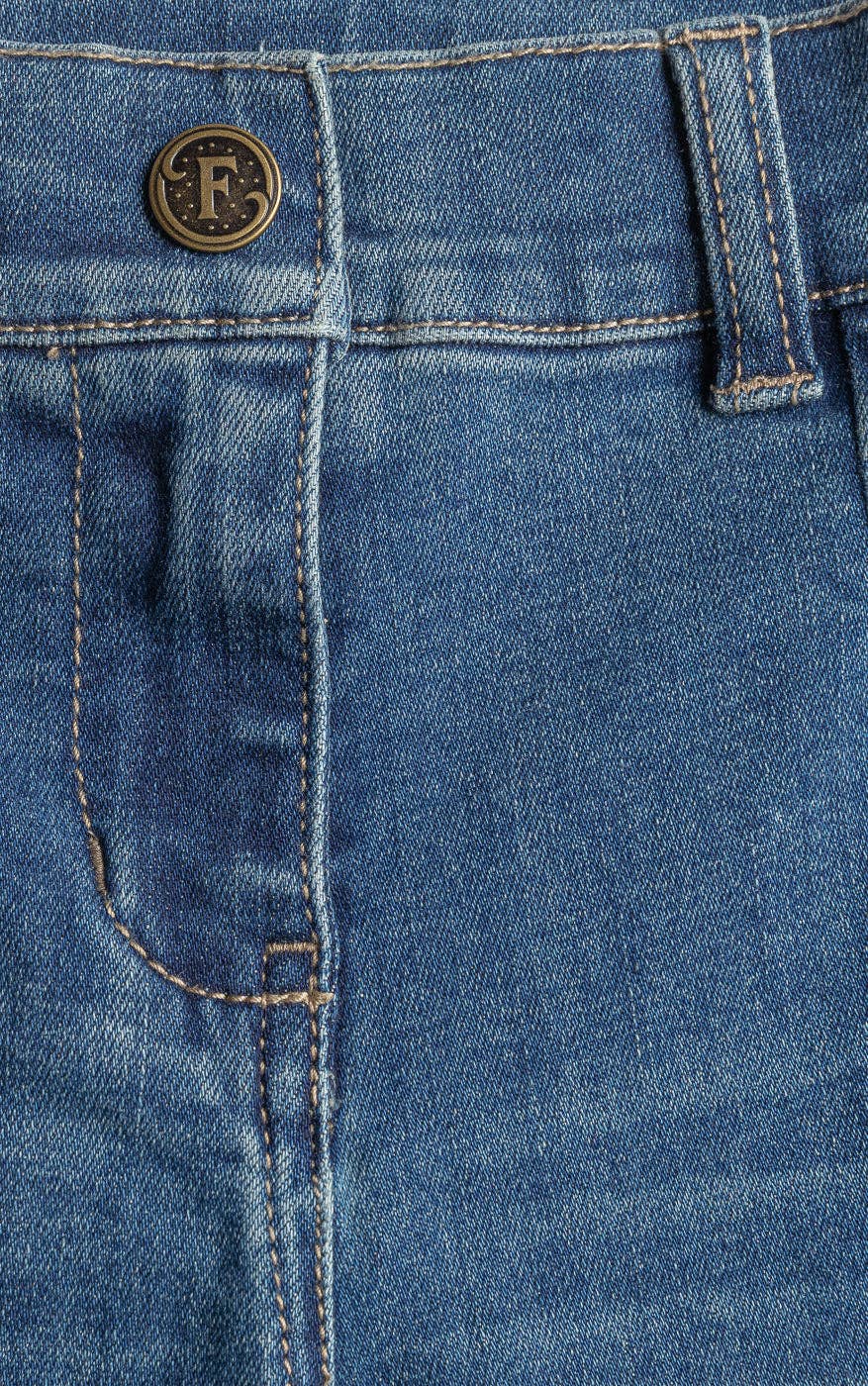 Close-up of blue denim fabric with a brand logo on a button.