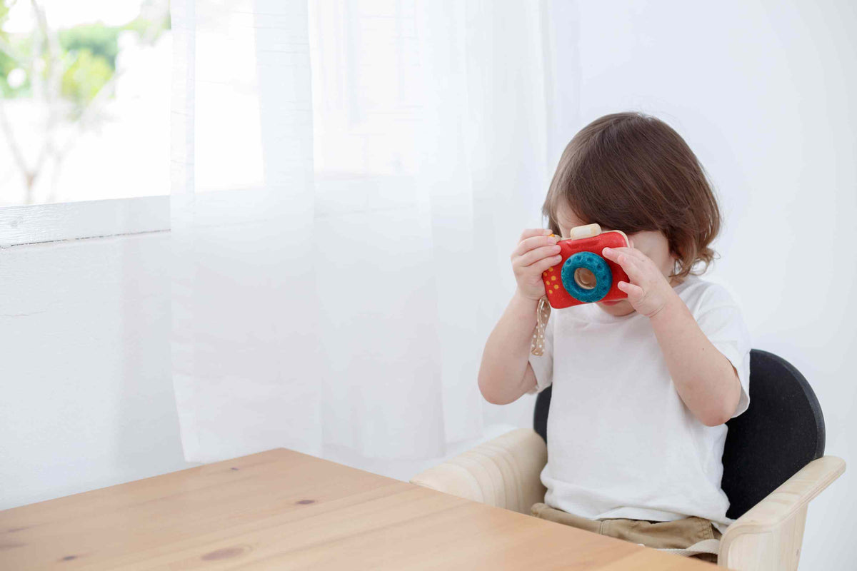 Child playing with a toy camera in a bright room