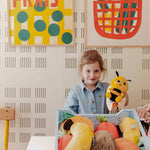 Child playing with toy Flipetz and vin a room with colorful abstract art on the wall.