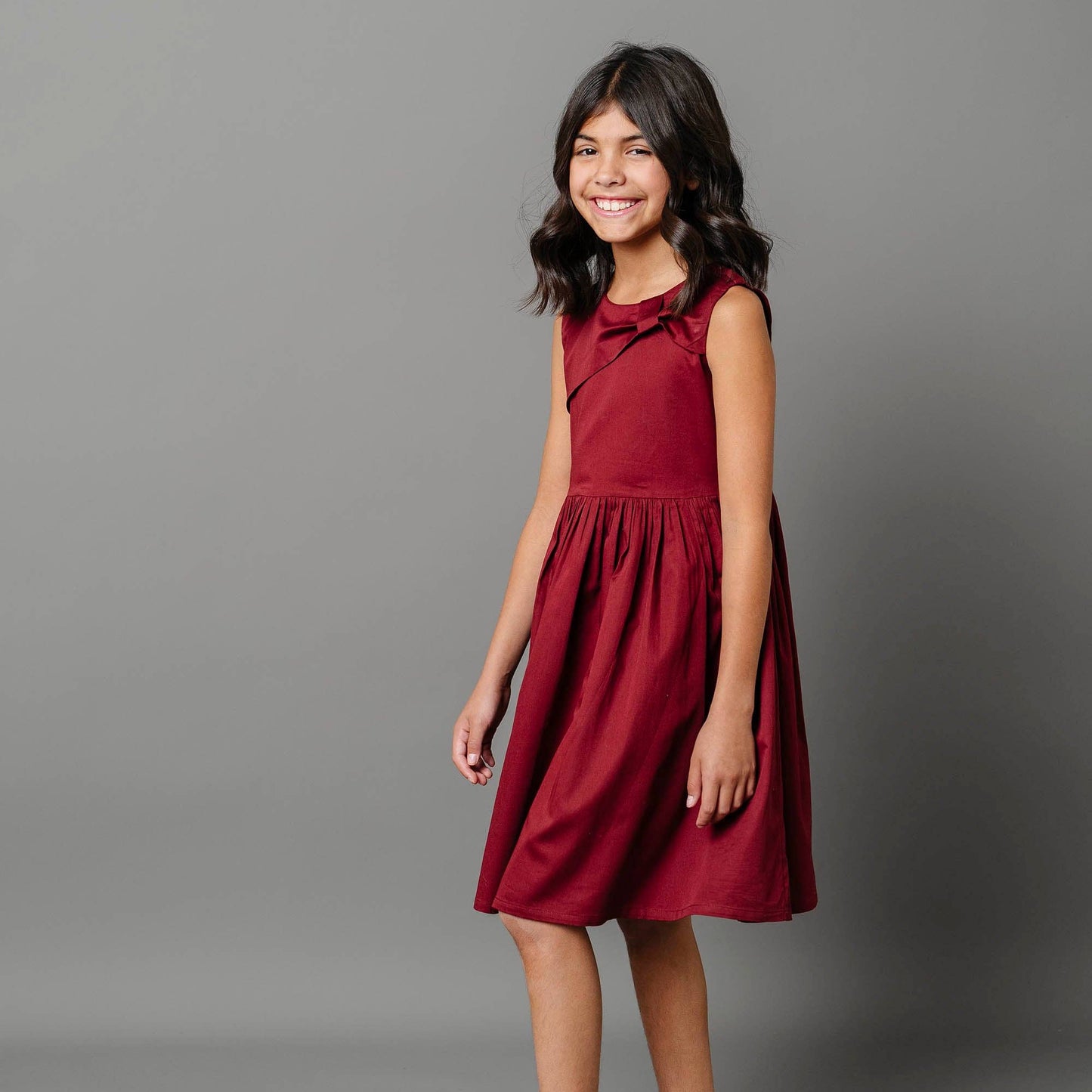 Young girl wearing a red dress against a gray background