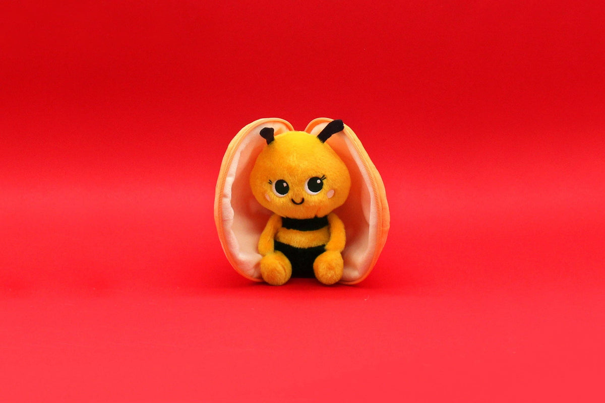 Small plush bee toy inside a shell on a red background