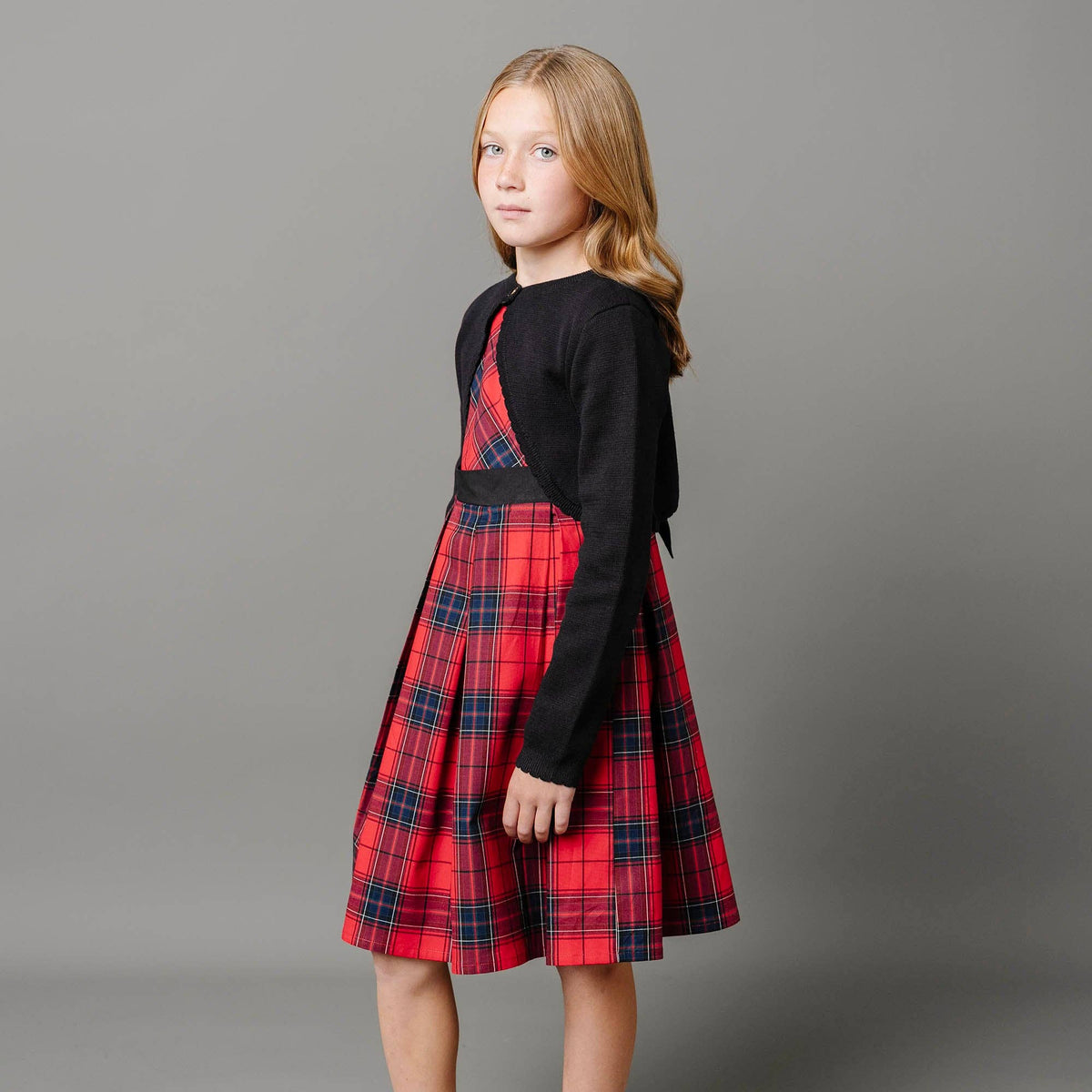 Girl wearing a red plaid dress with a black top on a gray background