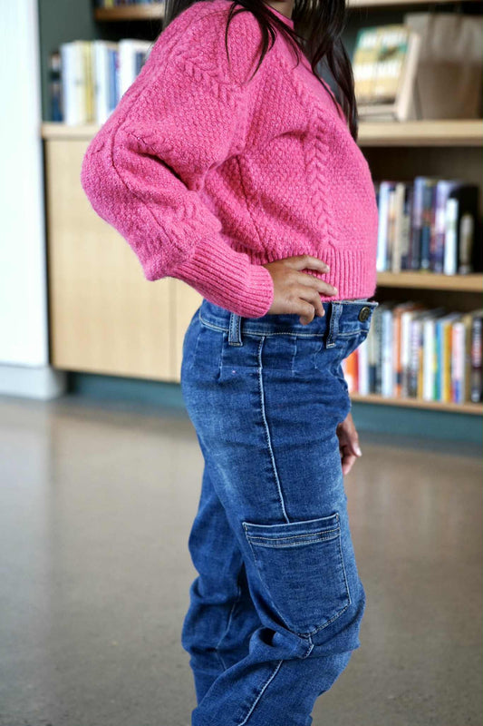 Person wearing a pink sweater and blue jeans in a library setting