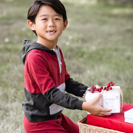 Child holding a small white box with red berries outdoors