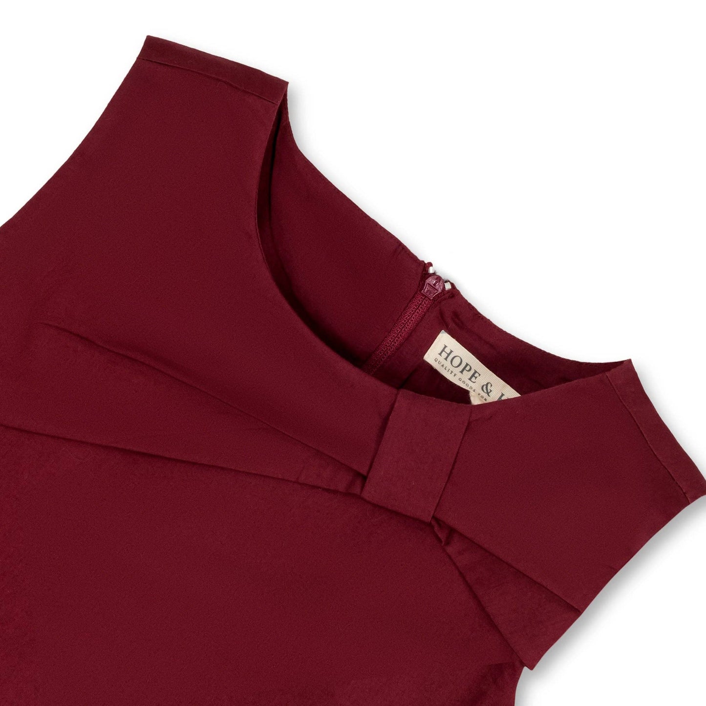 Maroon top of dress with a brand label on a white background