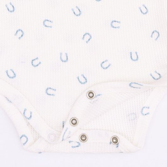 Close-up of a white ribbed baby bodysuit with a light blue horseshoe pattern and silver snap closures.