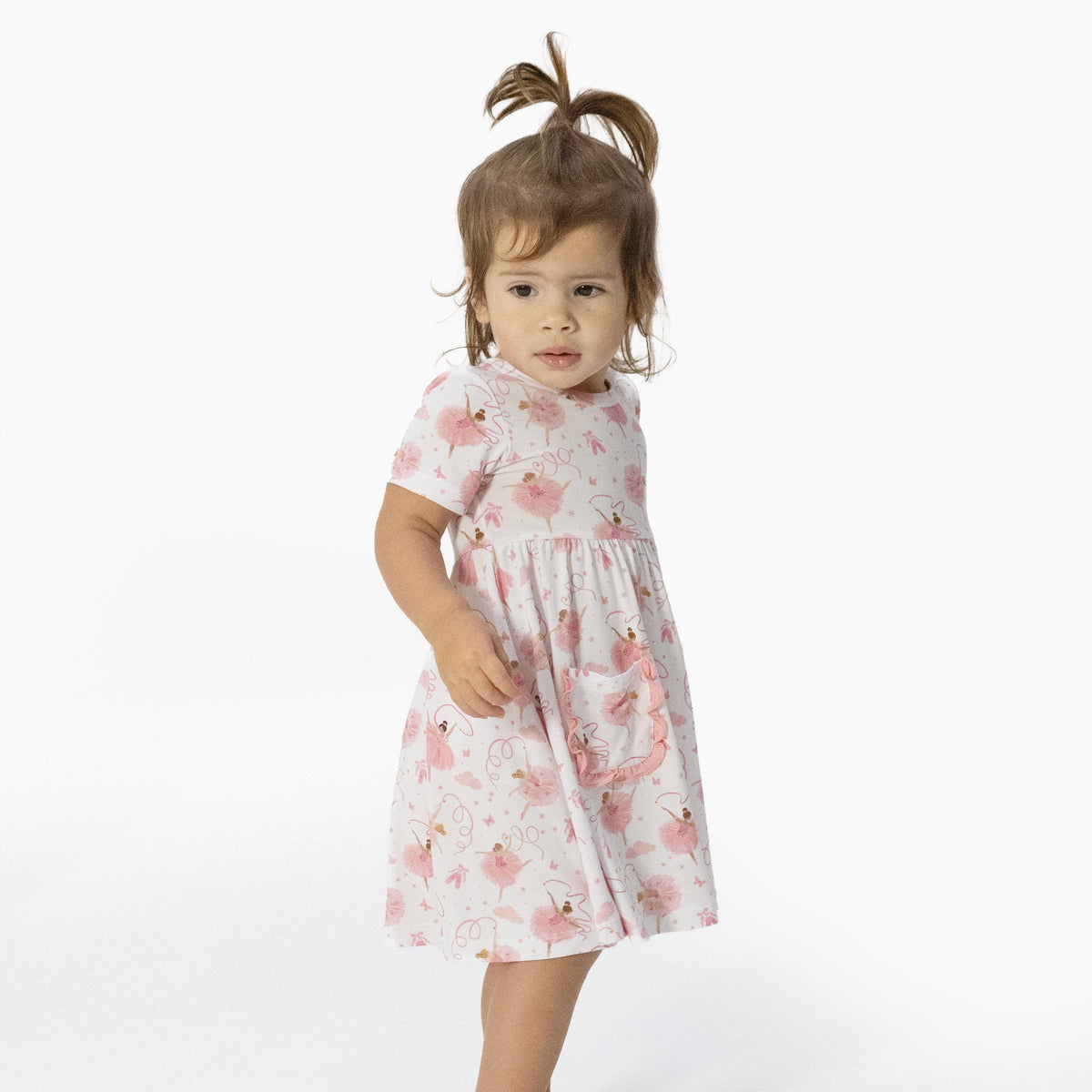 Young girl wearing a ballerina pattern dress on a white background
