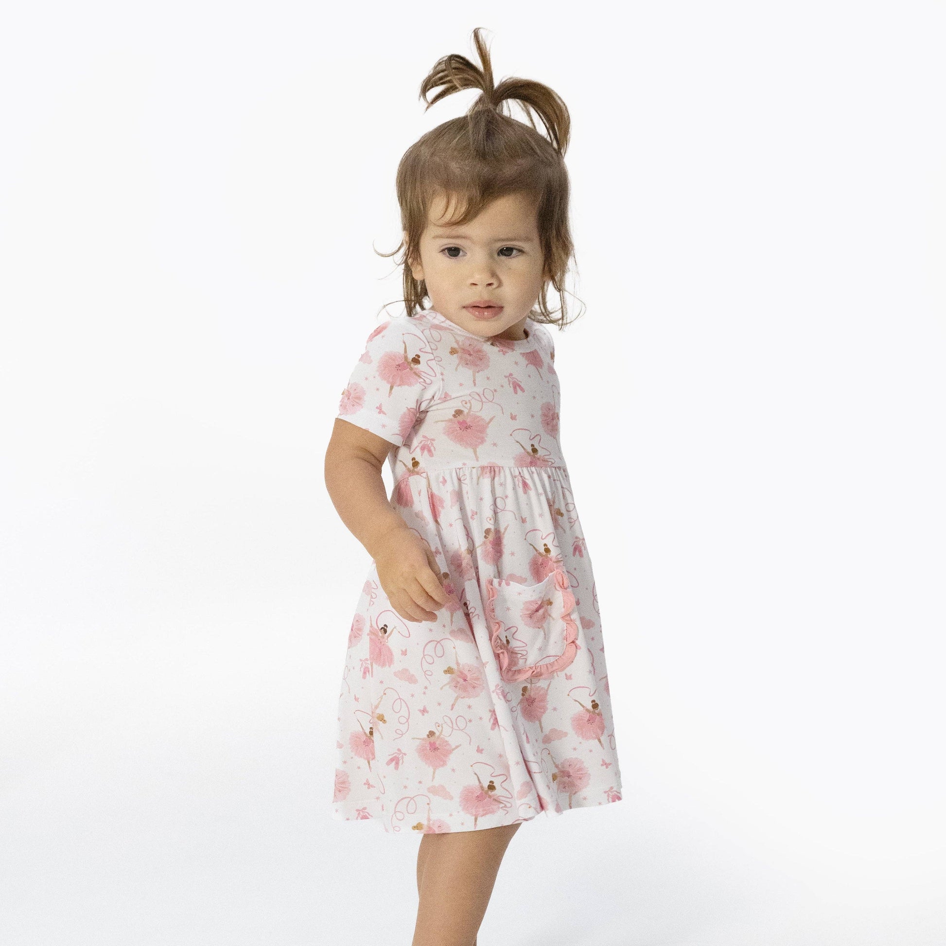 Young girl wearing a ballerina pattern dress on a white background