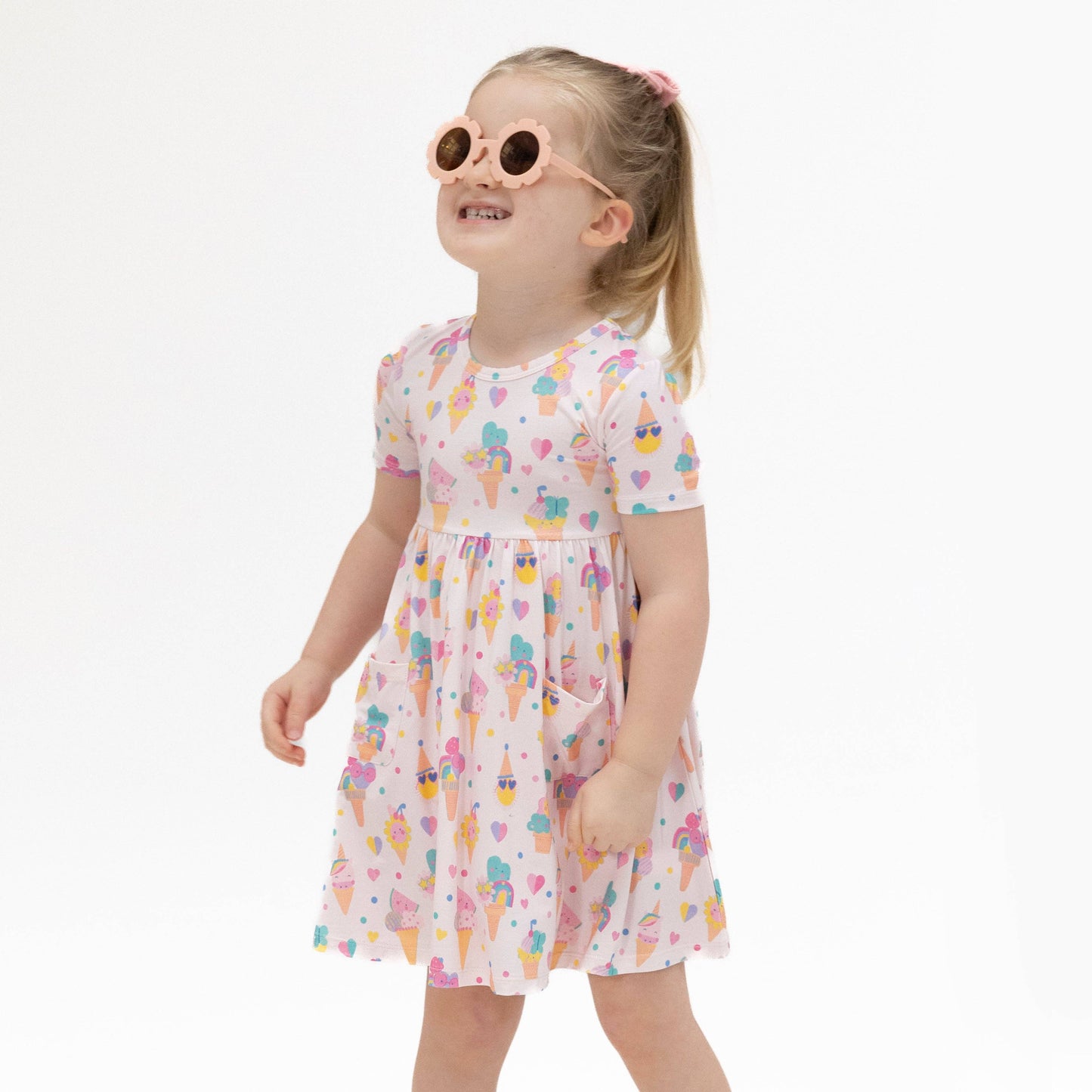 Young girl wearing a colorful ice cream print dress with a white background