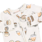 A baby zip-up sleeper in a warm off-white fabric, decorated with a cute cartoon pattern of coffee cups, iced drinks, and desserts.