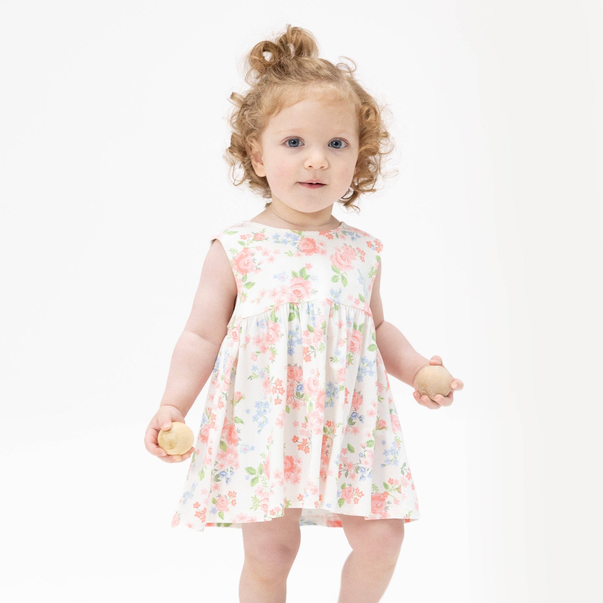 Young child wearing a floral dress on a white background
