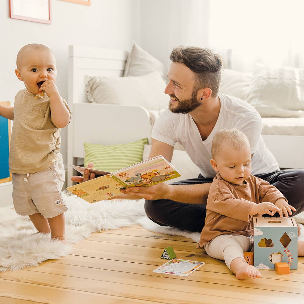 Man reading a book to two children in a living room.
