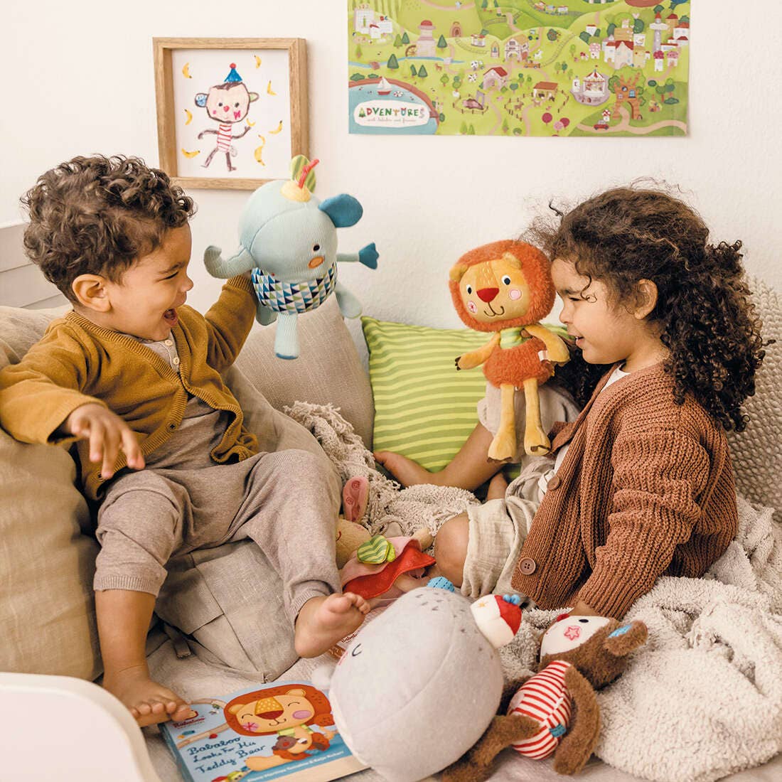 Two children sitting on a couch with Bababoo and friend plush and books, surrounded by colorful wall art.
