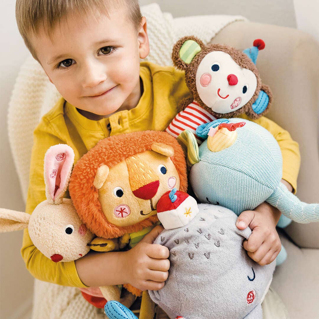 Child holding multiple Bababoo and friends plush toys in a cozy setting