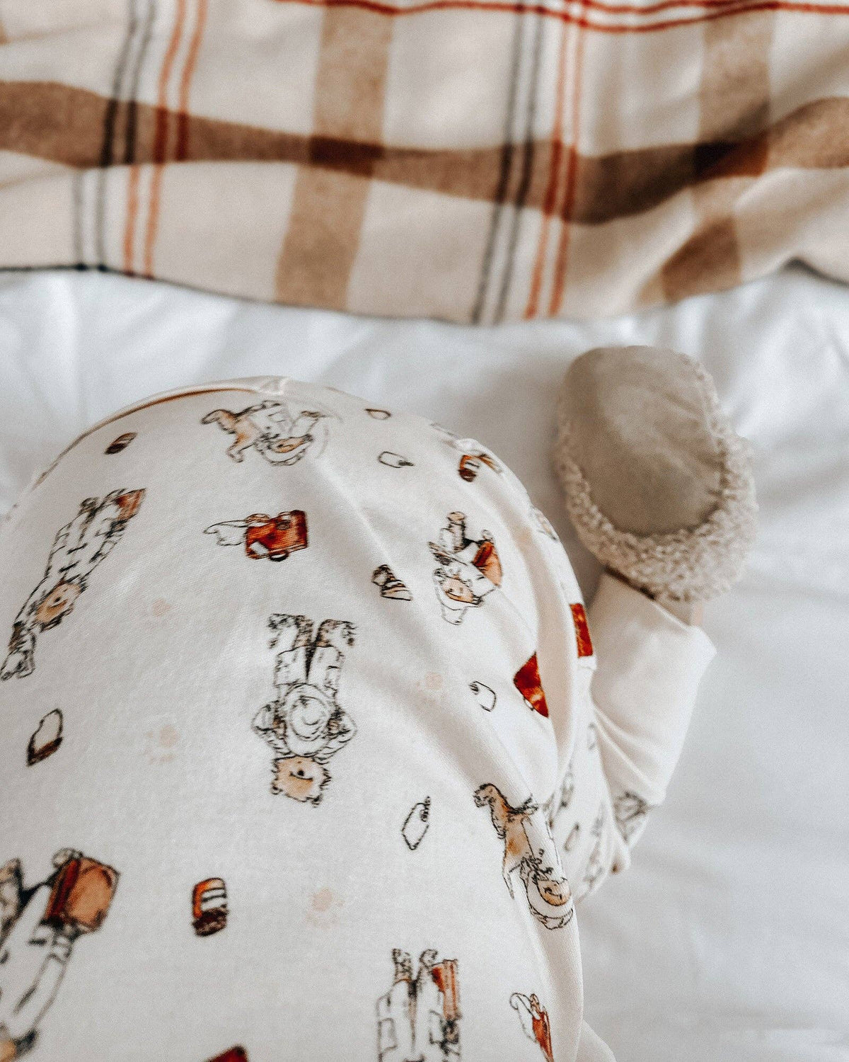 Baby outfit with Paddington bear on a white surface with plaid fabric in the background