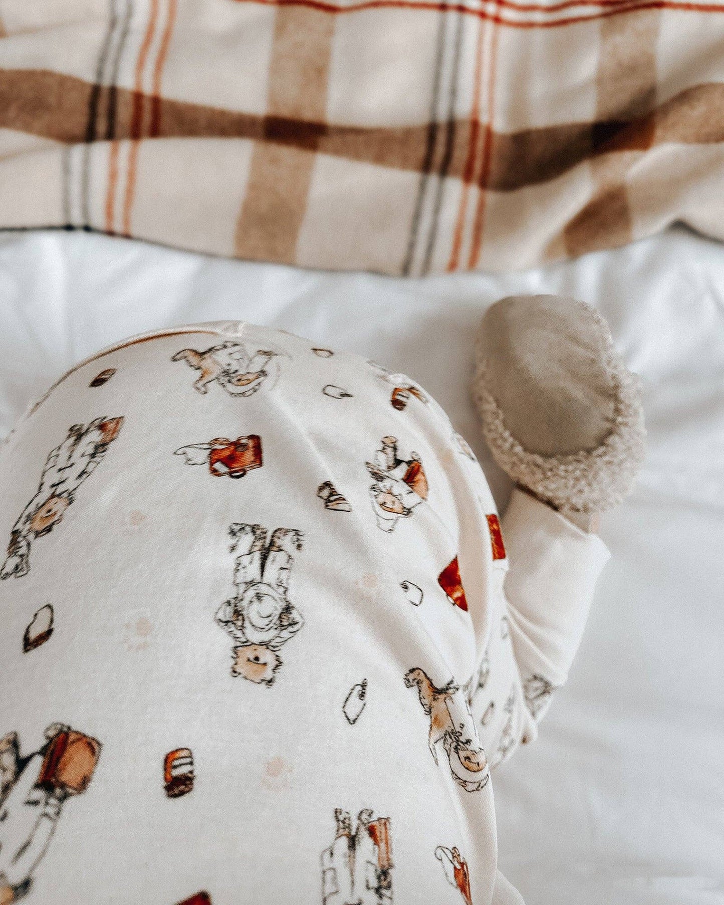 Baby outfit with Paddington bear on a white surface with plaid fabric in the background