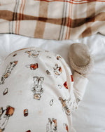Baby outfit with Paddington bear on a white surface with plaid fabric in the background