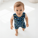 Baby wearing a blue romper with shark pattern on a white background