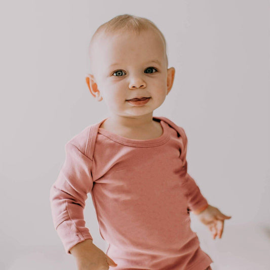 Baby wearing a pink long-sleeve shirt against a plain background