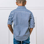 Back of boy wearing a blue and white checkered shirt against a light gray background