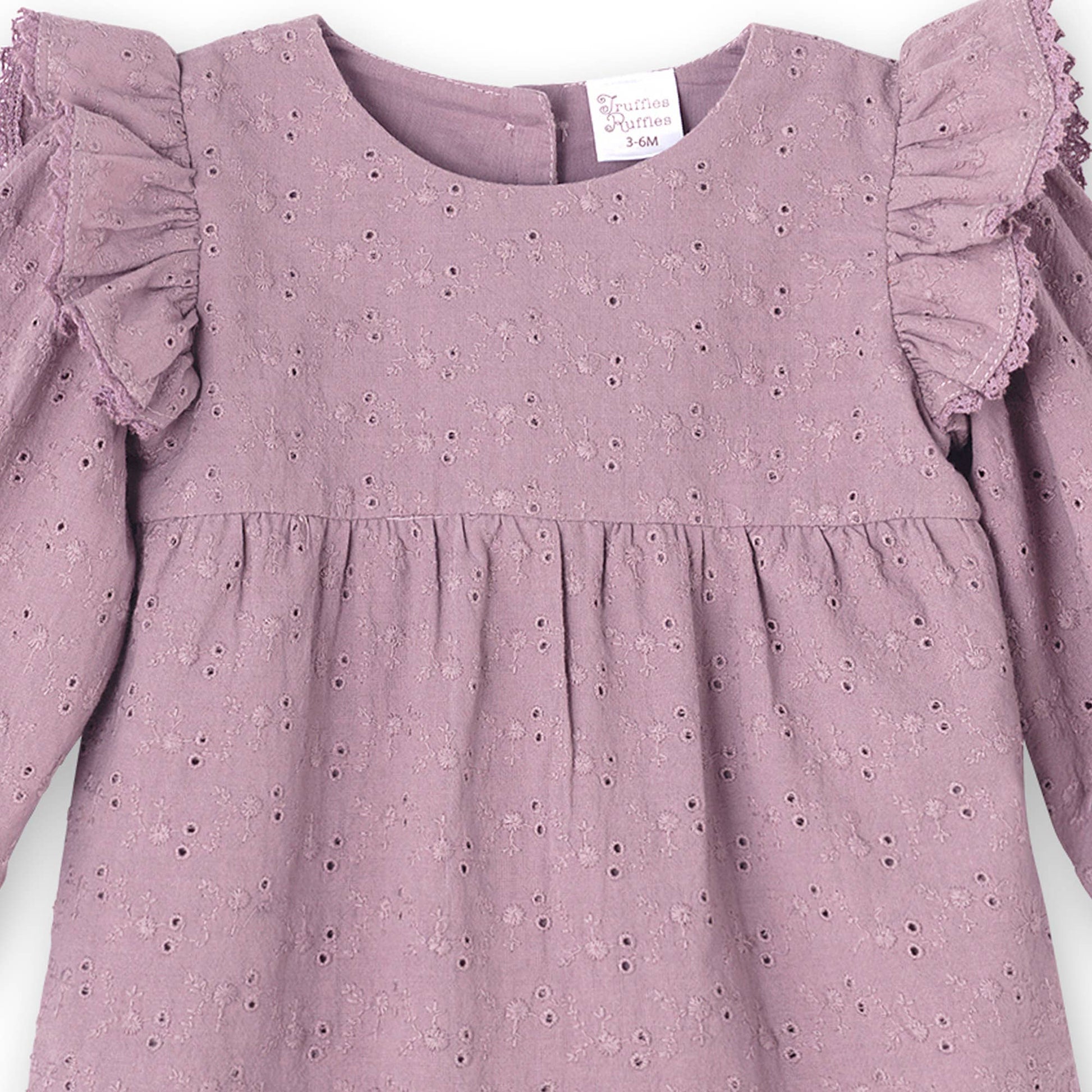 Close-up of mauve eyelet dress with ruffled sleeves on a white background