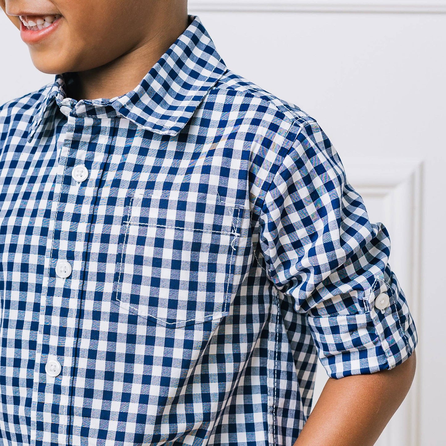 Child wearing a blue and white checkered shirt against a white background