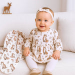 Baby sitting on a couch wearing a fox-patterned outfit with a matching blanket.