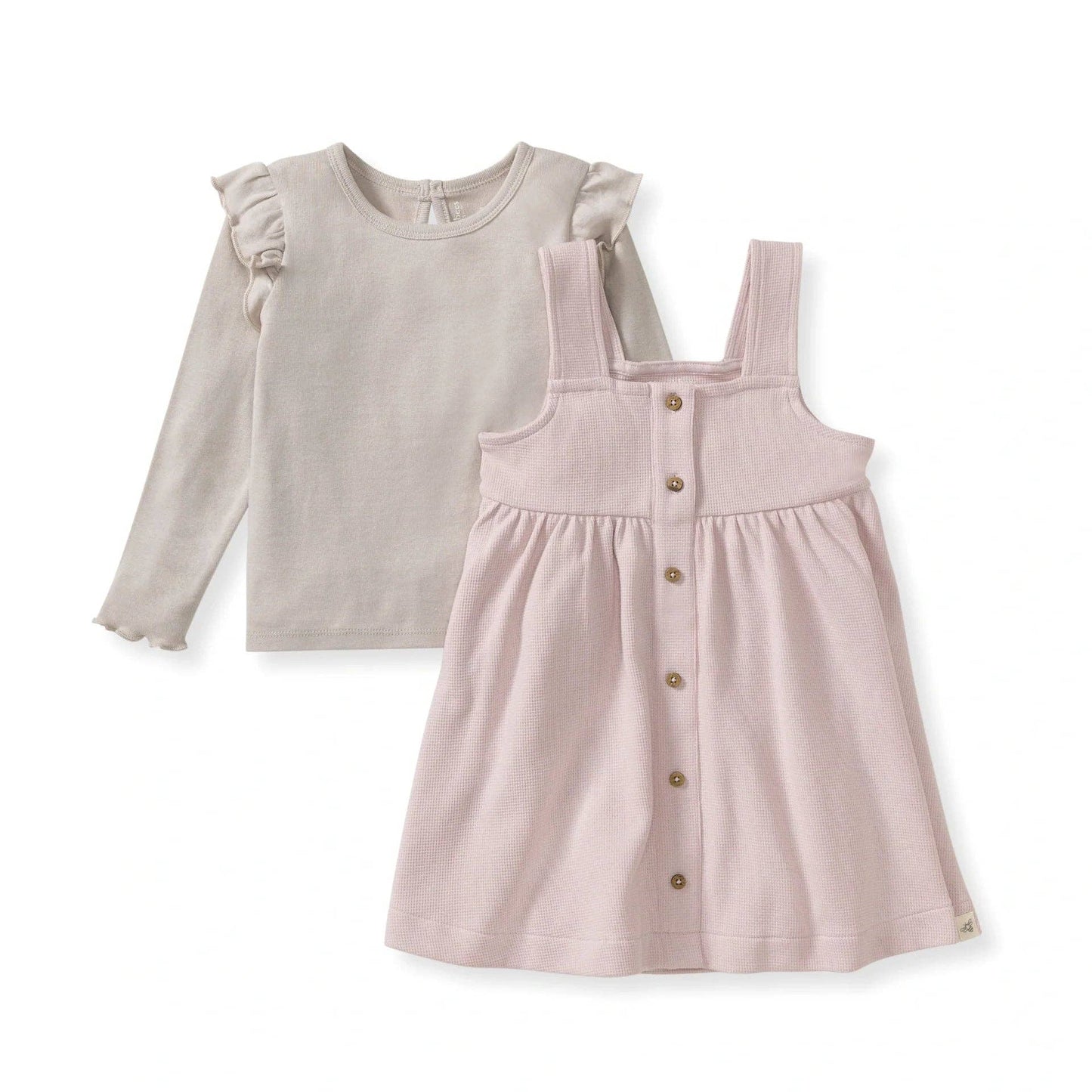 Children's outfit with beige long-sleeve top and pink pinafore dress on a white background