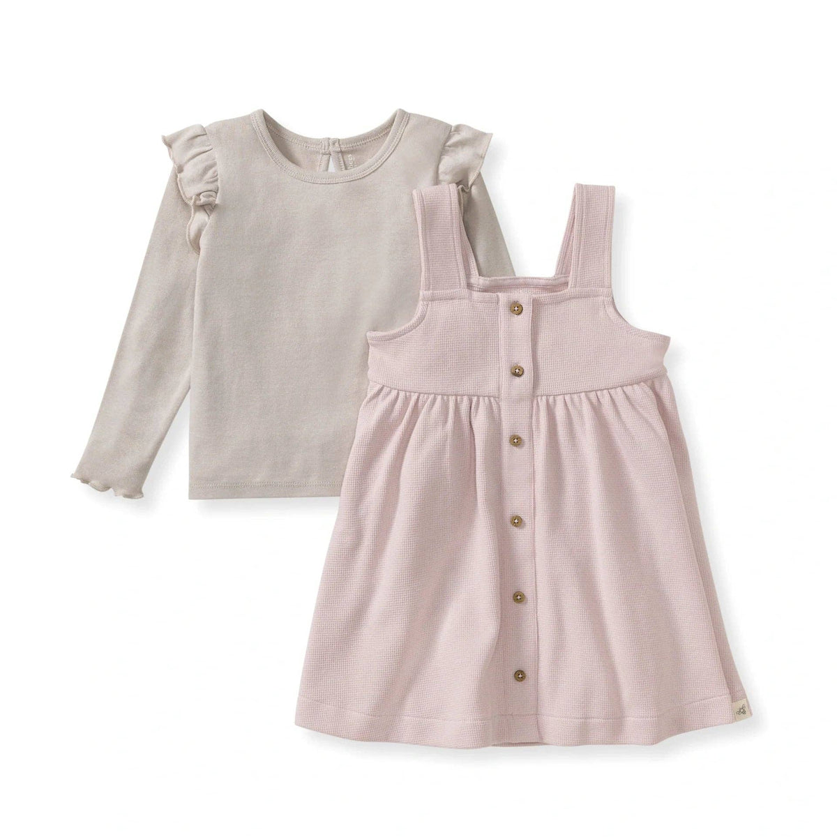 Children's outfit with beige long-sleeve top and pink pinafore dress on a white background