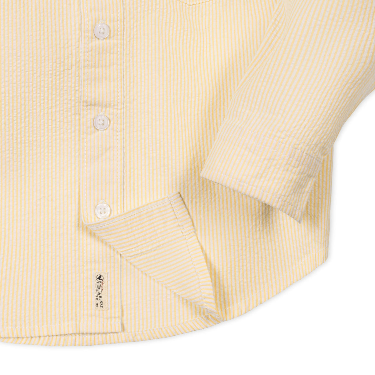 Close-up of a yellow striped shirt with a sleeve and button details on a white background