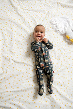 Baby wearing Harry Potter coverall lying on a white blanket with yellow star patterns