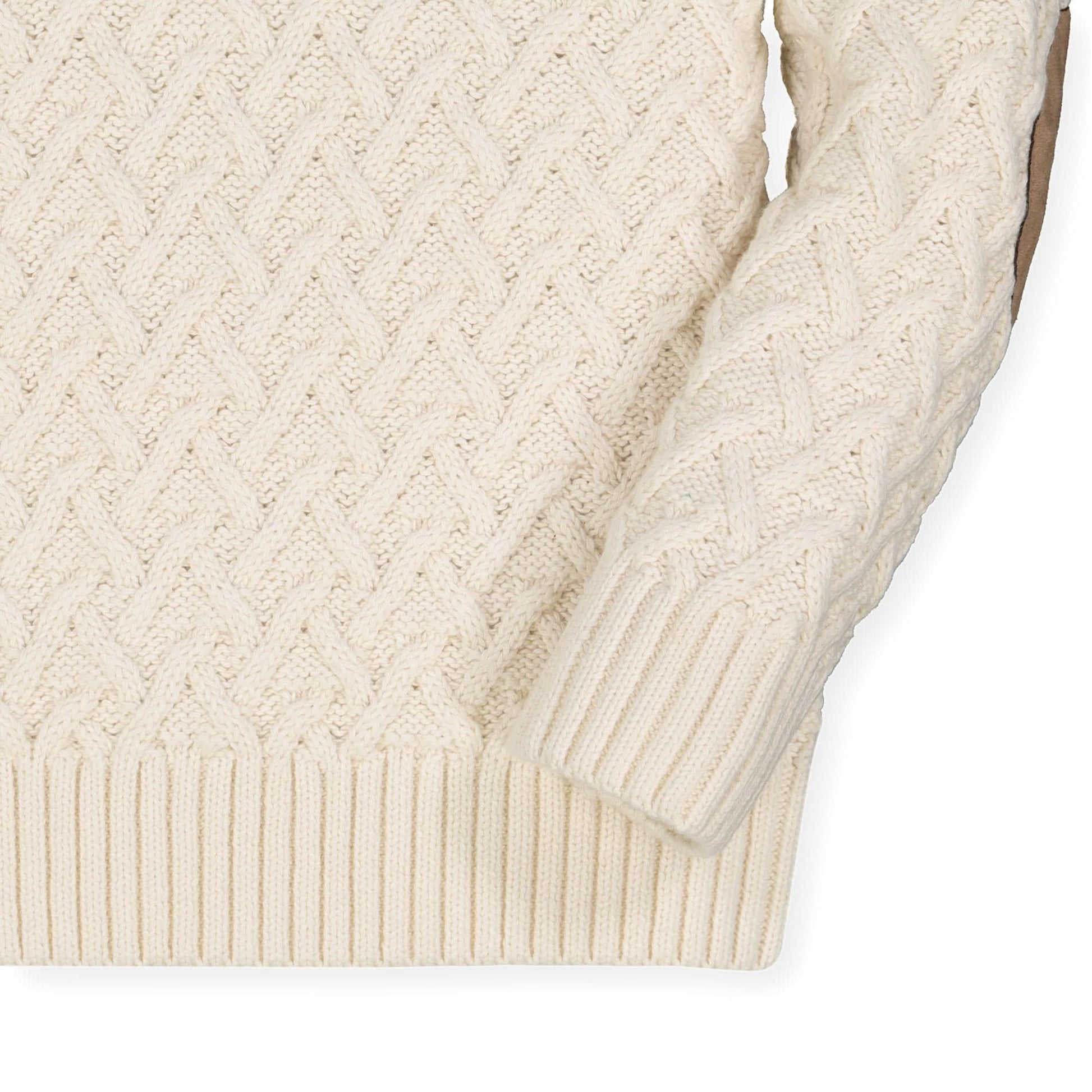 Close-up of a cream-colored cable knit sweater on a white background