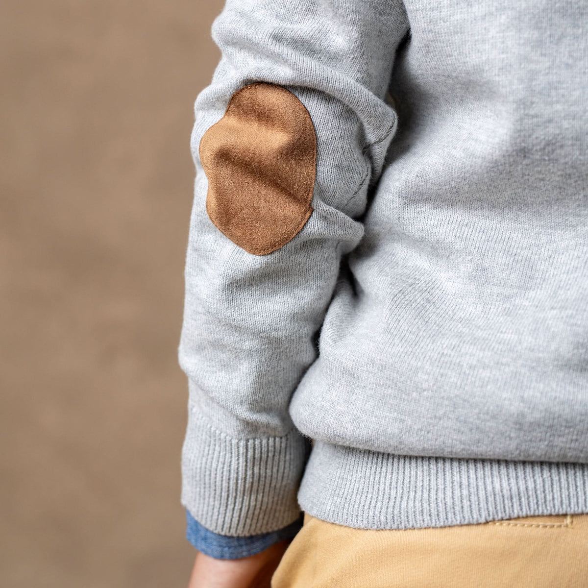 Gray sweater with a brown elbow patch on a beige background